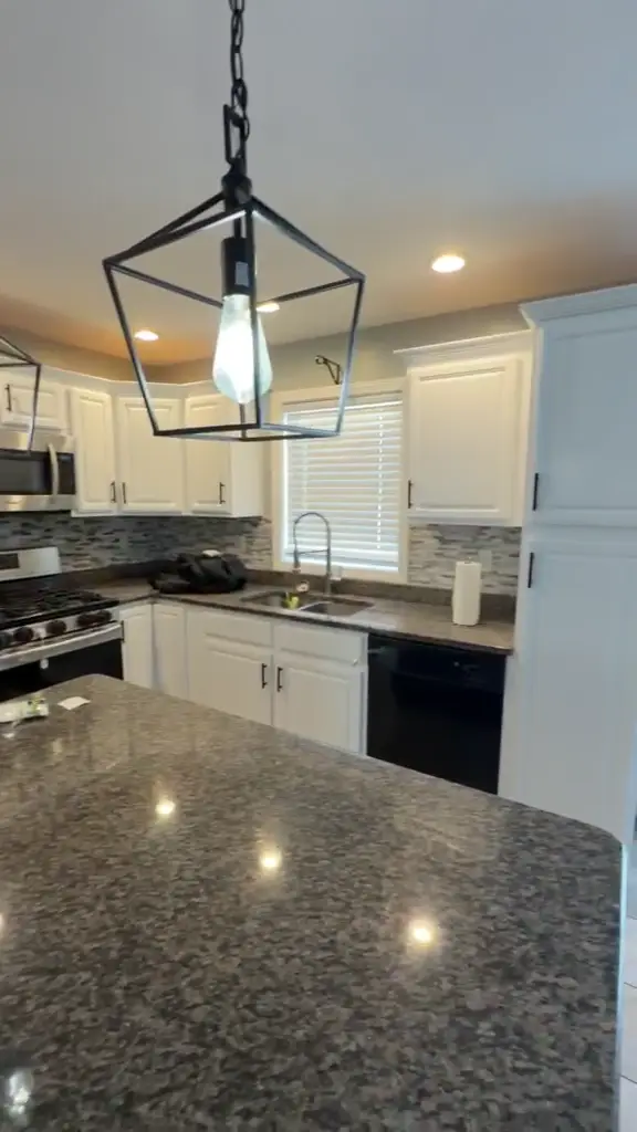A completed white cabinet kitchen with dark countertops and island.