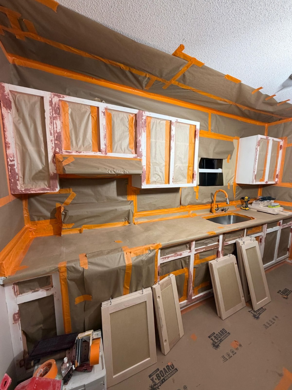 Kitchen fully masked with paper and tape, countertops and surrounding surfaces protected
